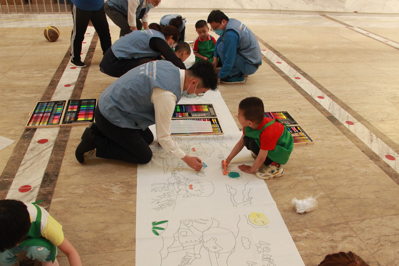 포스코 중국 가공센터 임직원이 샹위자폐증회복센터 어린이들과 환경보호 현수막 그림 그리기를 하고 있다